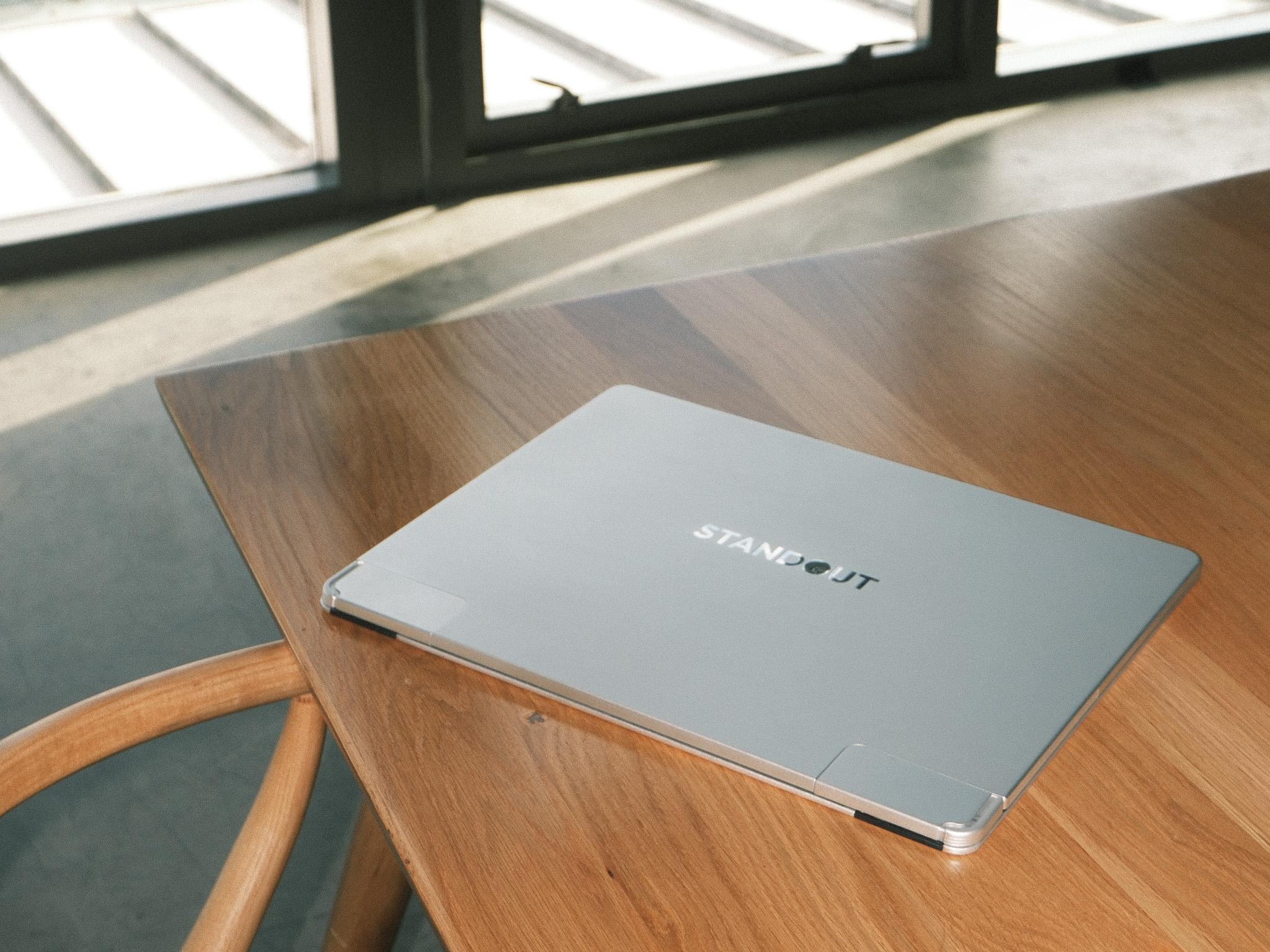 Standout portable monitor paired with a MacBook on a wooden desk overlooking a scenic lake view.