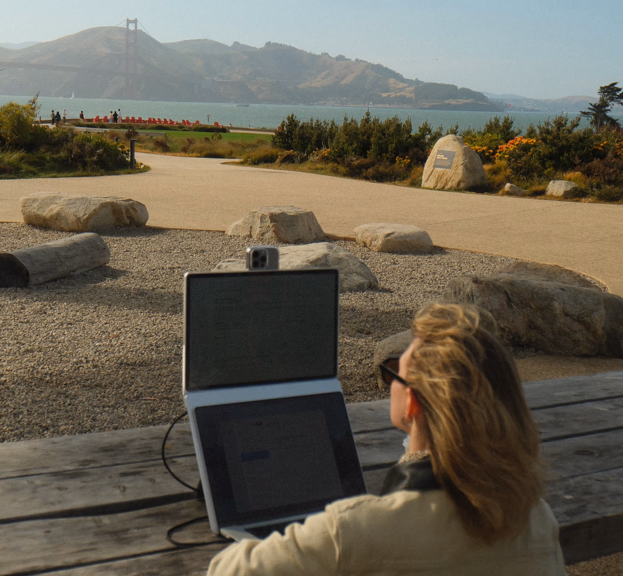 Standout portable monitor paired with a MacBook on a wooden desk overlooking a scenic lake view.