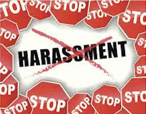 A cluster of red stop signs surrounds the word HARASSMENT, which is crossed out with a red X, symbolizing a call to stop harassment.