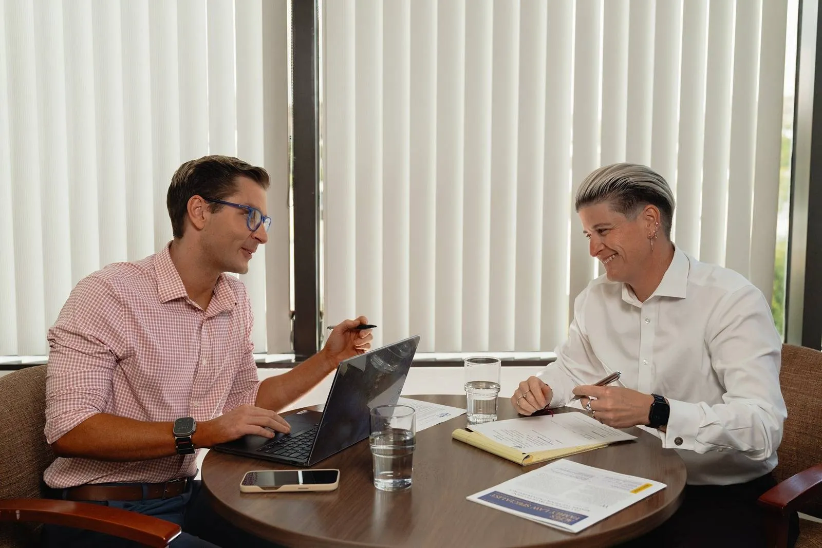 Cage & Miles family law attorneys Jillian Duggan-Herd and Kevin Alexander sit and talk together at desk.