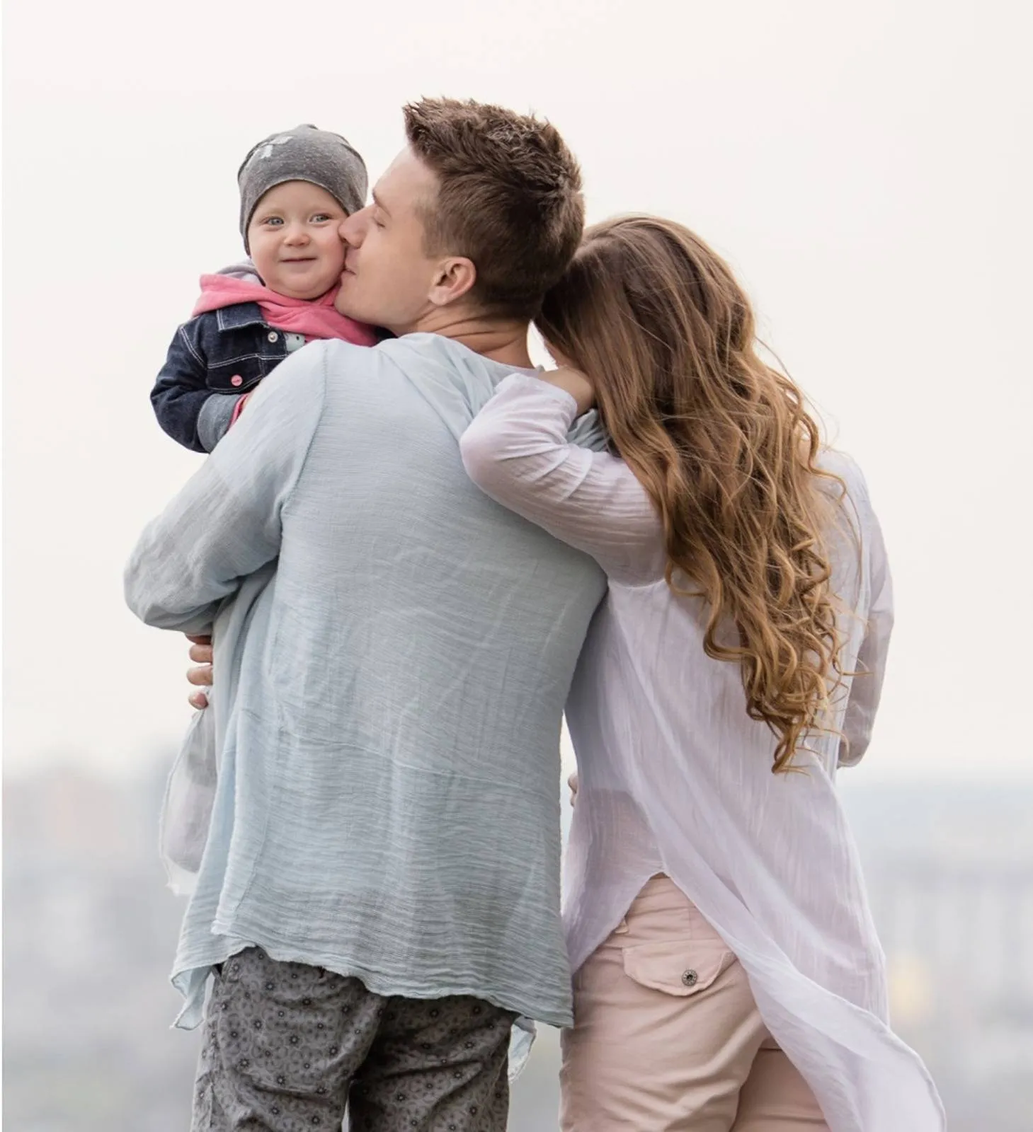 Father holding baby while standing beside mother.