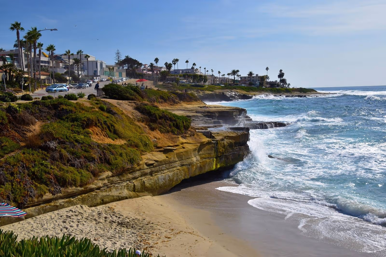 Waves hitting rocky cliffs and sandy beach along the La Jolla.