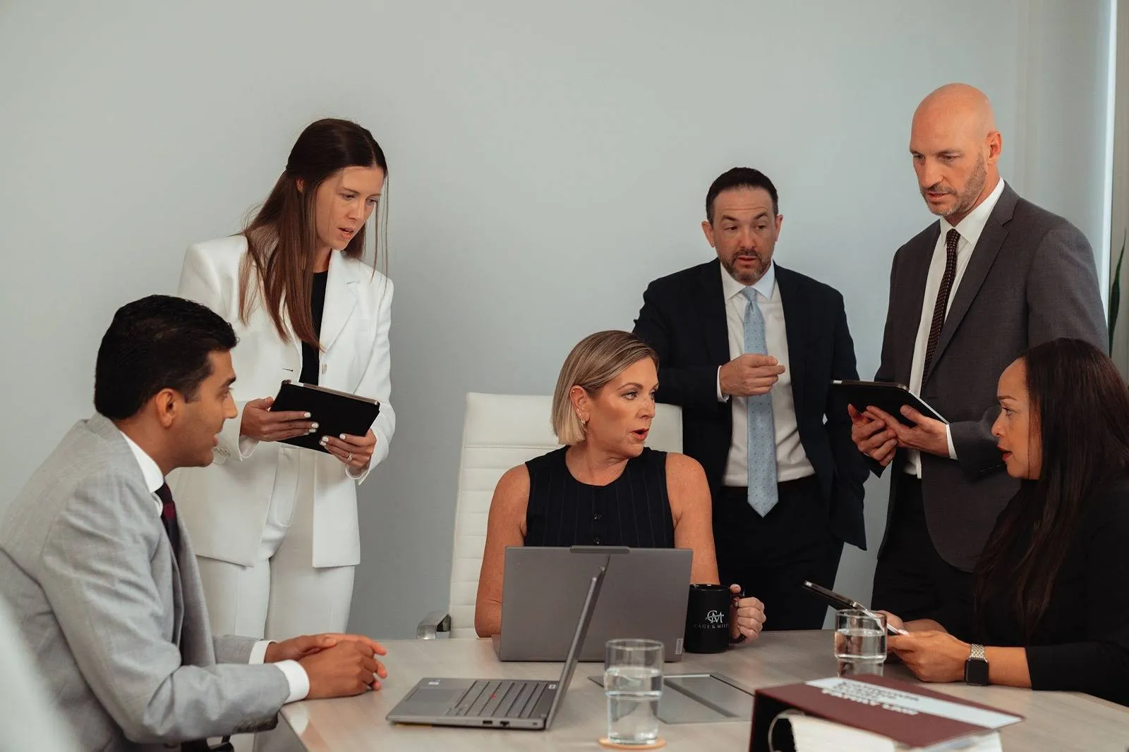 Cage & Miles founding partner, Shannon Miles, sits at conference table surrounded by attorneys.