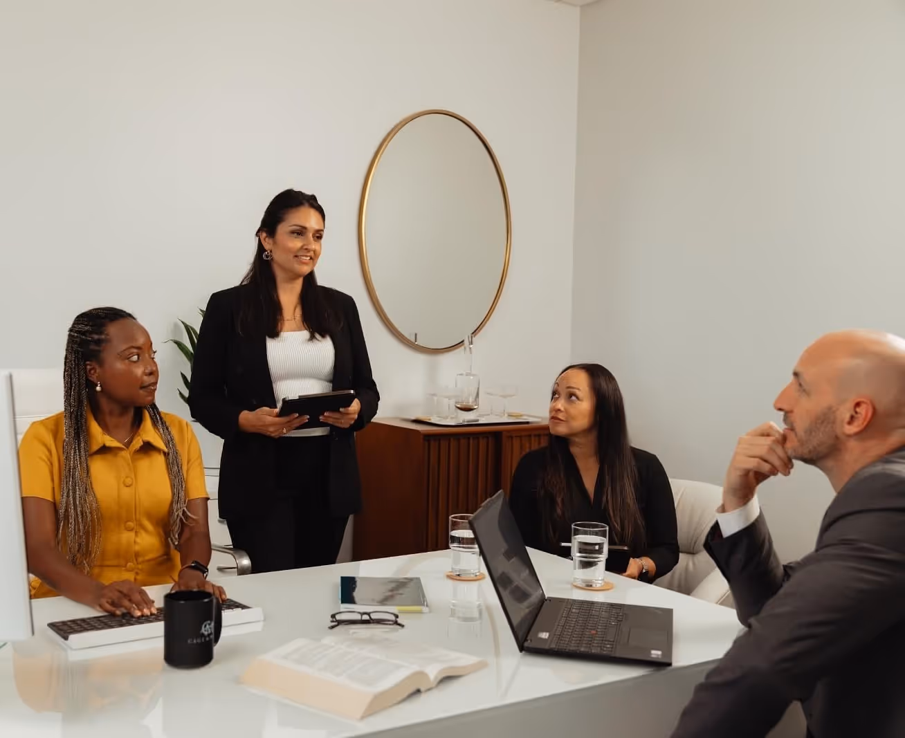 Cage & Miles family law attorneys Mehry Mohseni, Deanne Arthur, and James Dooley speaking with a colleague at a desk.