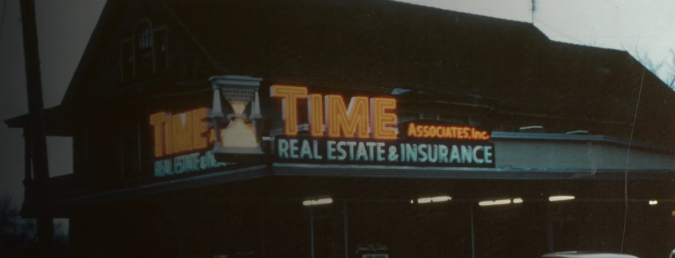 Illuminated sign for Time Associates Real Estate & Insurance with hourglass icon