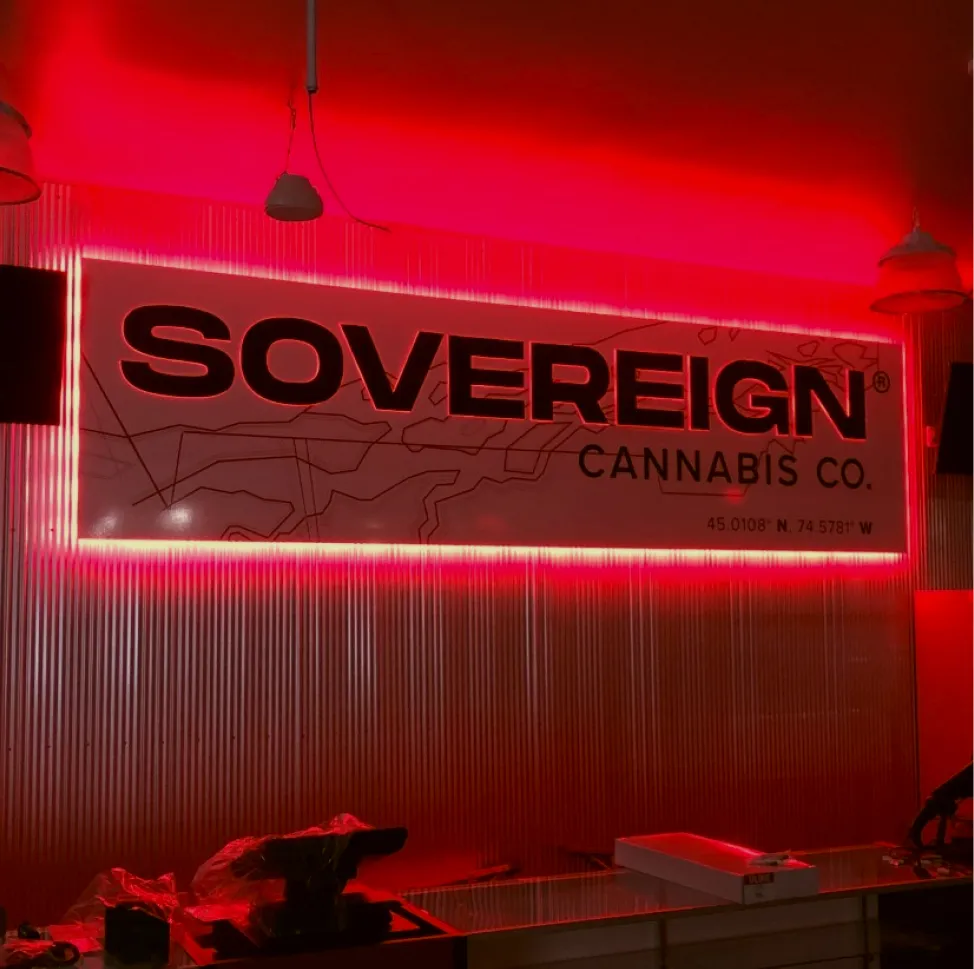 Backlit indoor signage for Sovereign Cannabis Co. glowing in red inside a retail space.