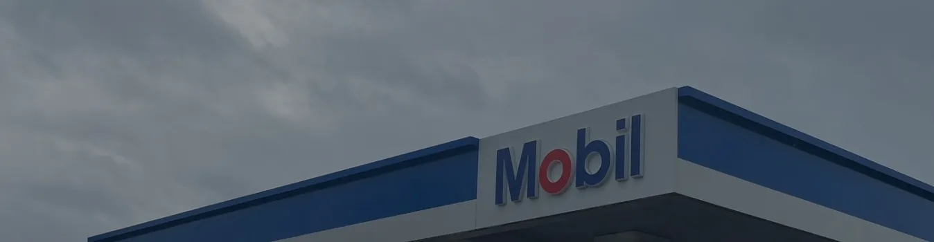 Mobil gas station canopy with branded blue and red signage against cloudy sky