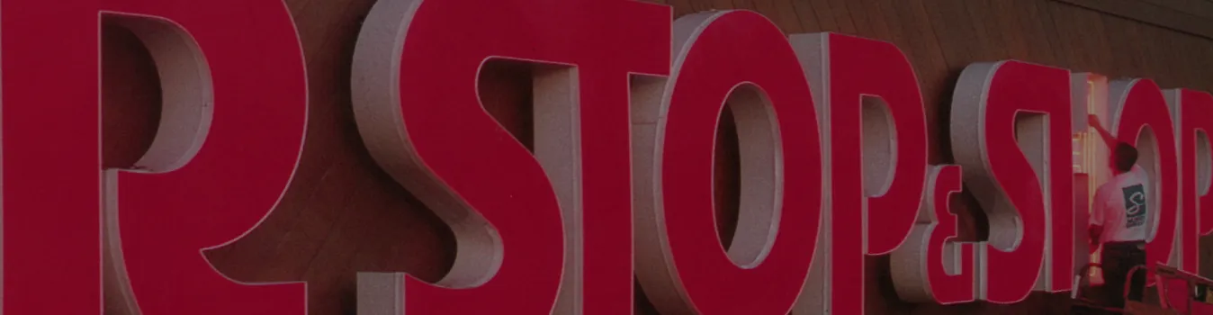 Technician installing red 3D Stop & Shop letters on retail storefront facade