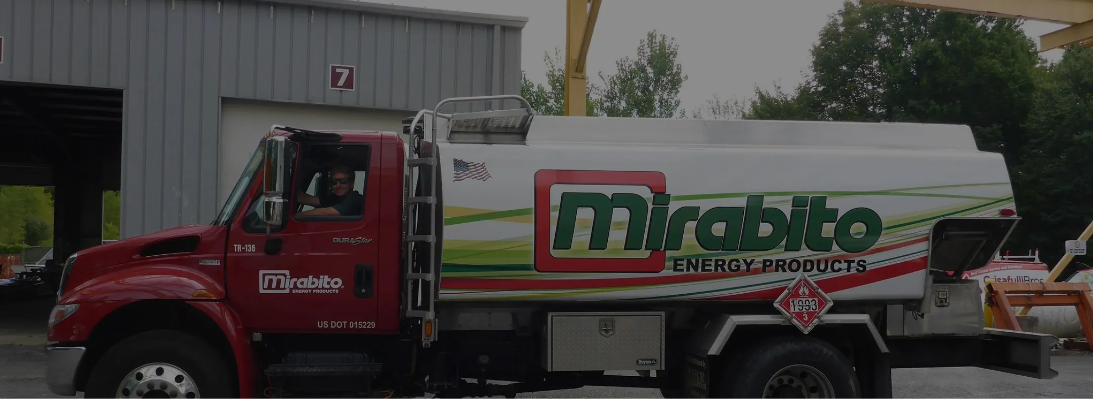 Red and white Mirabito Energy Products fuel delivery truck parked outside a warehouse.