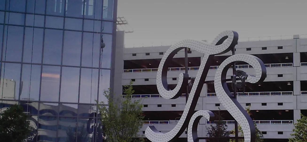 Large-scale decorative monogram sculpture installed in urban development near parking structure