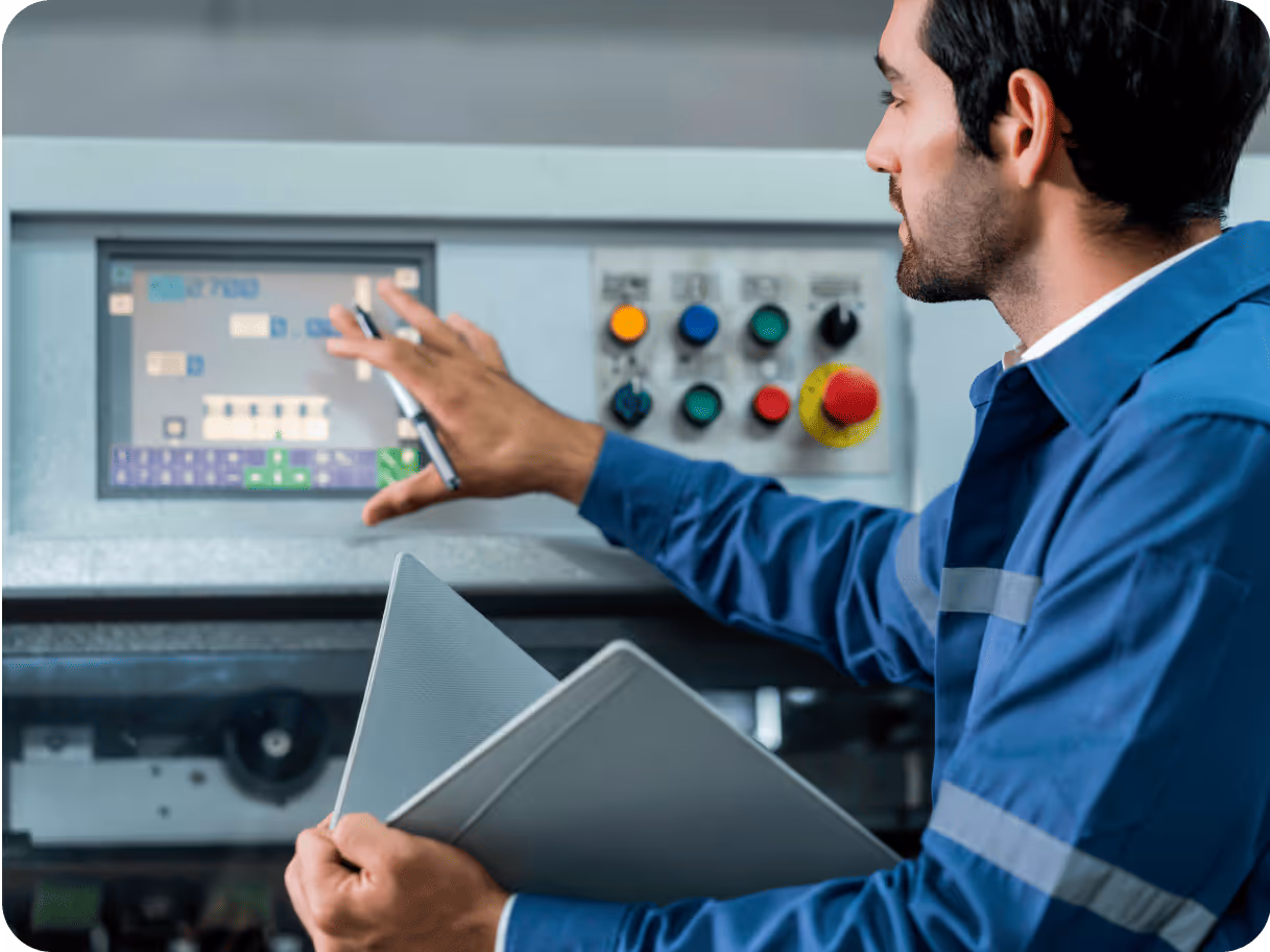 Technician using a touch screen on a machine control panel while holding documents.