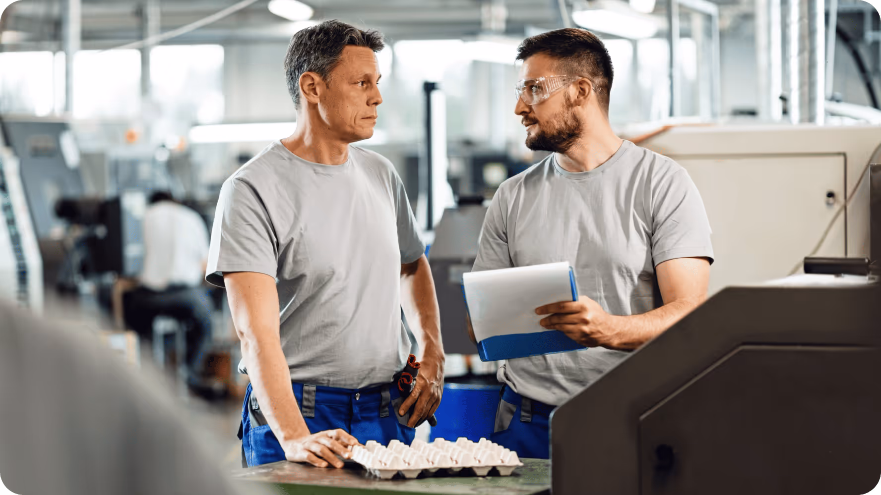 Two factory workers discussing documents in an industrial setting