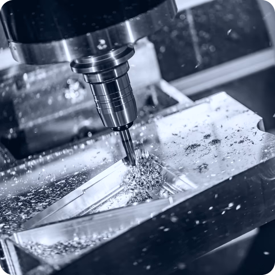 CNC milling machine shaping a metal block with visible chips.