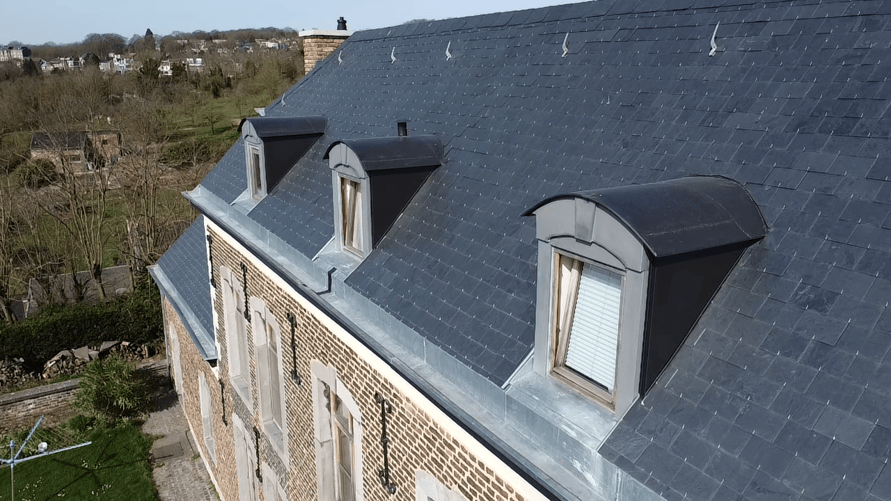 Image montrant le recouvrement des boiseries, des joues et de la toiture de barbacanes recouvertes de zinc quartz et anthracite. 