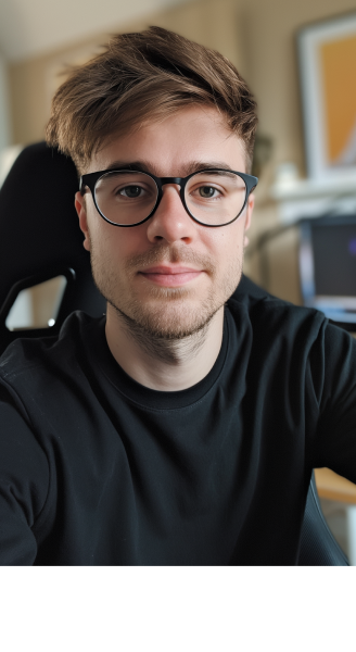 A man with glasses sitting in front of a computer desk.