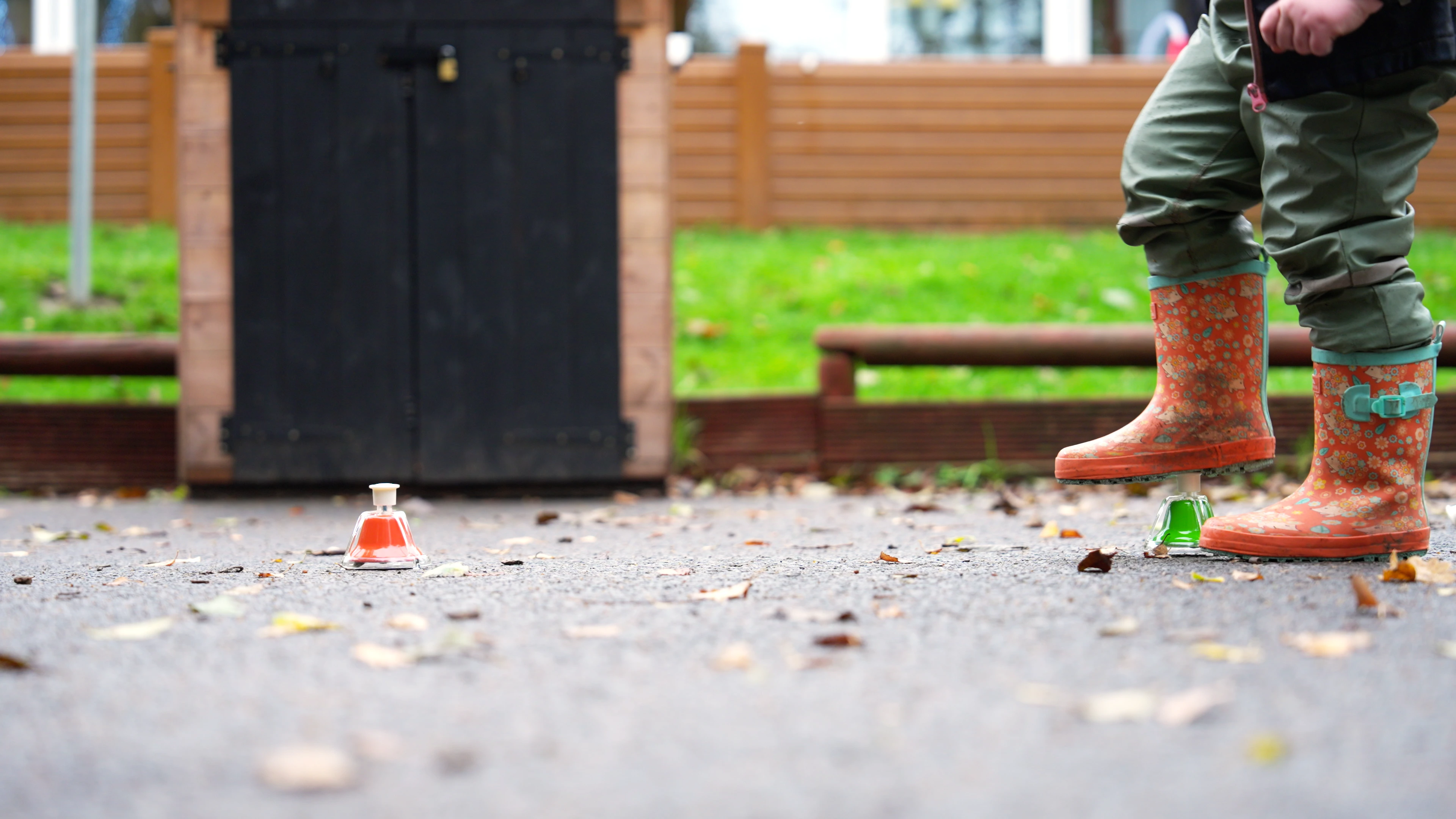 Child in patterned rain boots stepping on tactile music objects in playground. Observational storytelling moment from “Loop” mini documentary by Rendah Films.