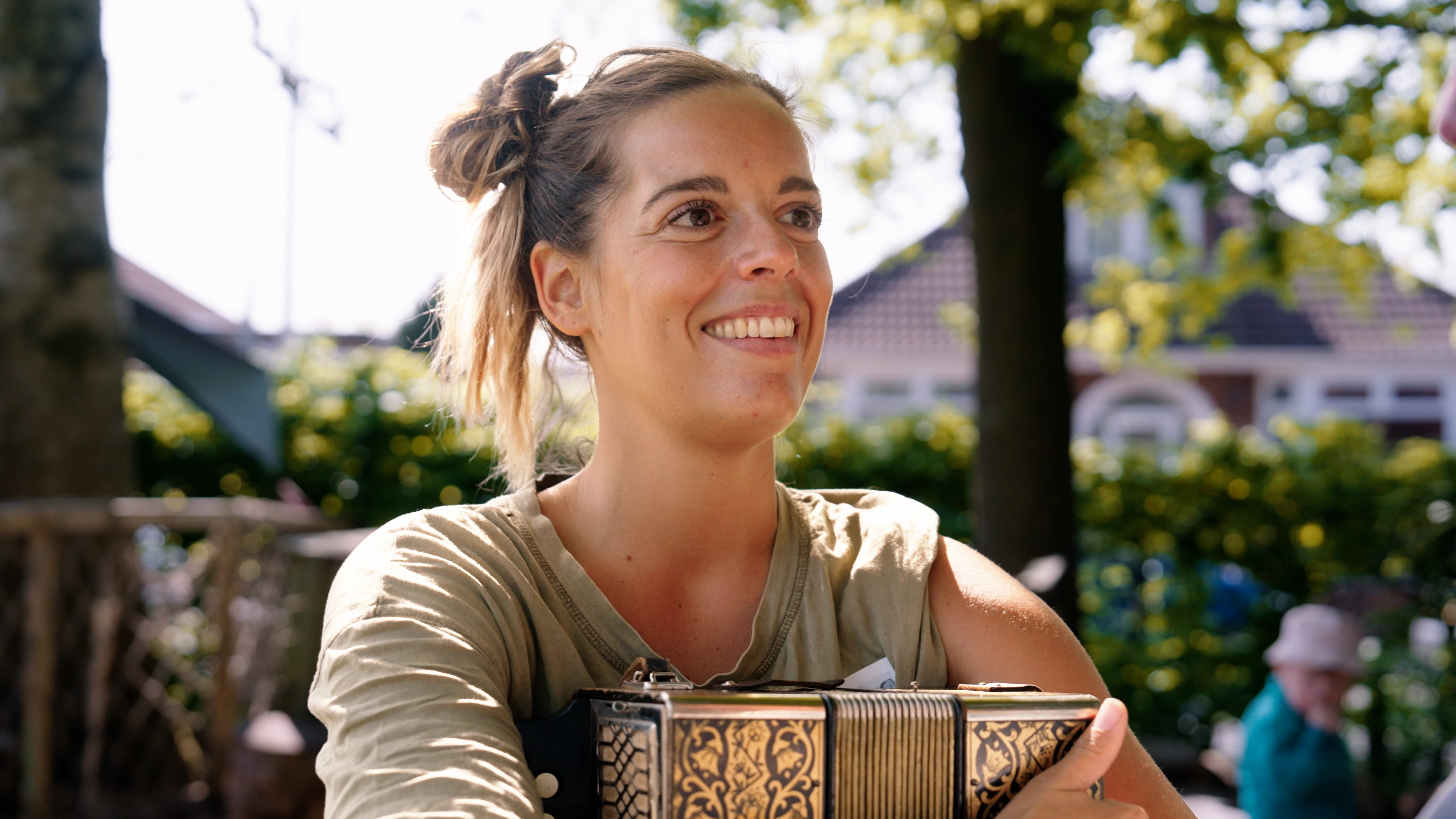 Female musician holding accordion outdoors in natural sunlight. Cinematic talking head shot from “Loop” mini documentary by Rendah Films highlighting authentic human stories.