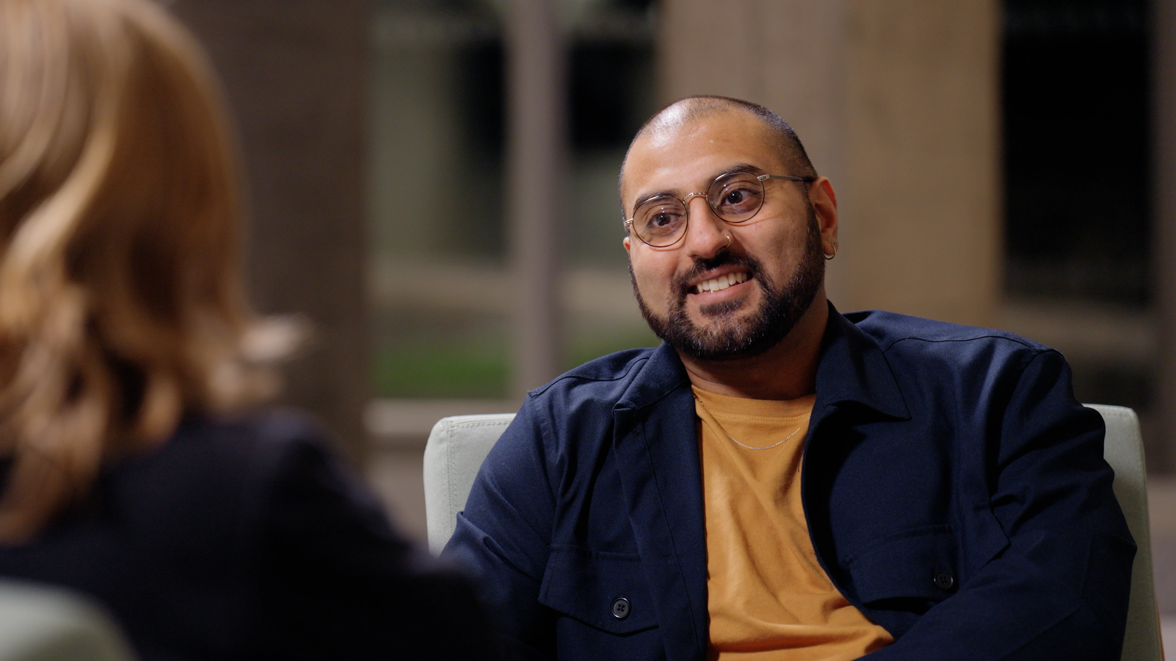Over-the-shoulder framing of Akshay Sharma speaking in interview at Jewry Wall Leicester filmed by Rendah Films production