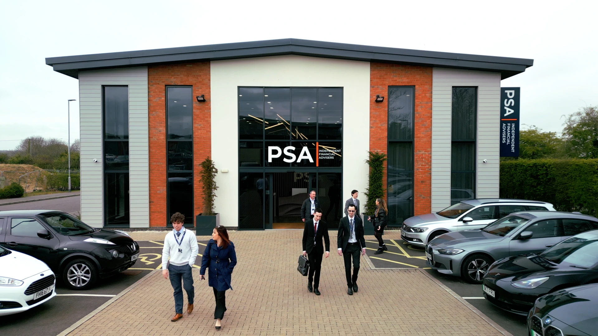 Wide shot of PSA Financial Services office exterior with team members exiting modern headquarters | corporate video production by Rendah Films