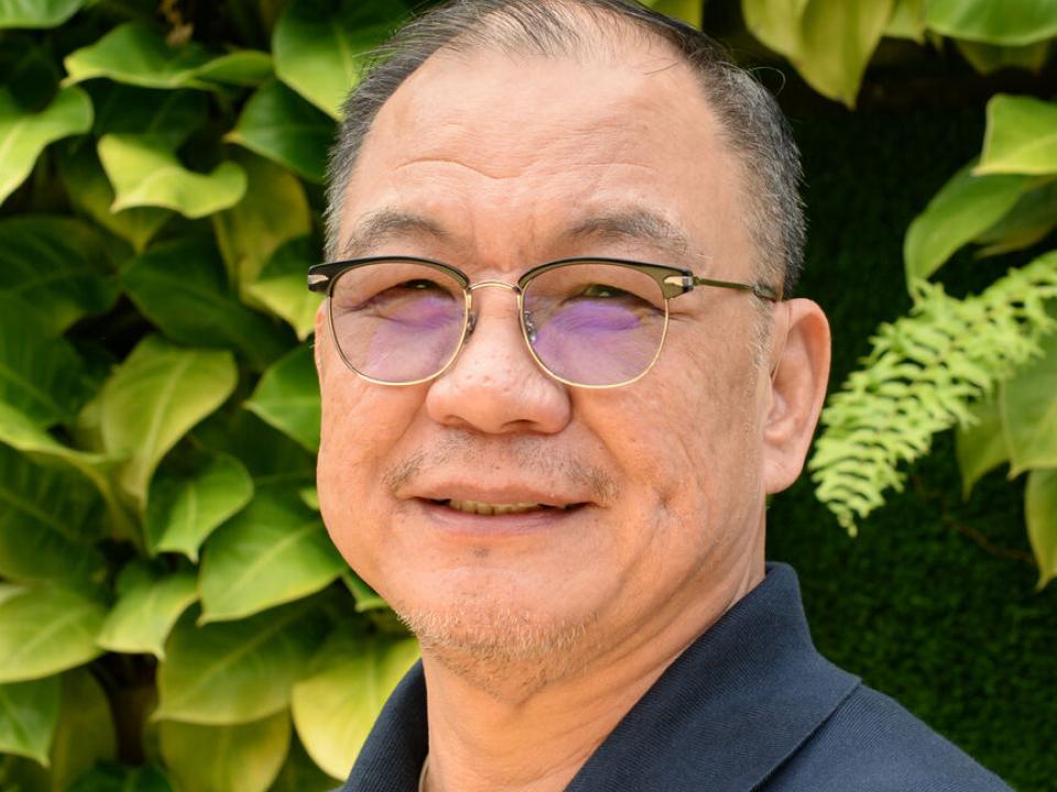Mission worker smiling in a lush New Zealand backdrop with a heart for overseas outreach. OM New Zealand