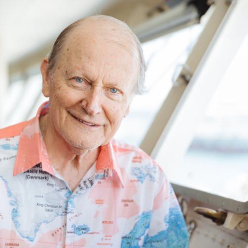 A Kiwi missionary smiling proudly in a map-print shirt for global mission work. OM New Zealand