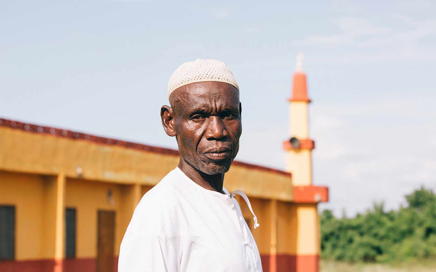 Mission worker standing before a vibrant yellow mosque in a foreign overseas setting. OM New Zealand
