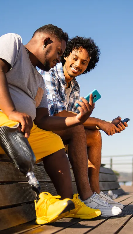 Two men smiling and laughing while sitting and looking at phone
