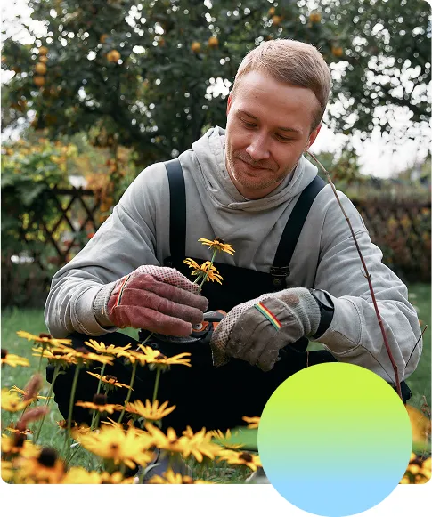 Man looking happy while gardening outdoors with some healthy flowers