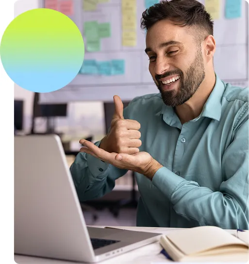 Man smiling and signing at a laptop screen