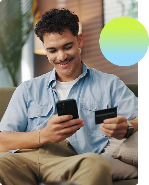 Man looking confidently at his card and his phone and making some kind of transaction