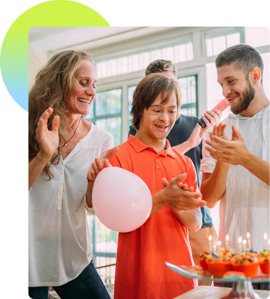 A happy young man with a disability being surrounded by family celebrating his birthday