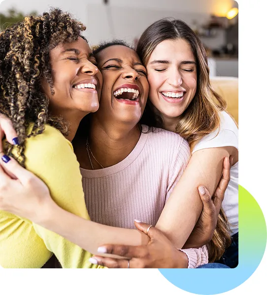 Three female friends smiling and laughing and hugging