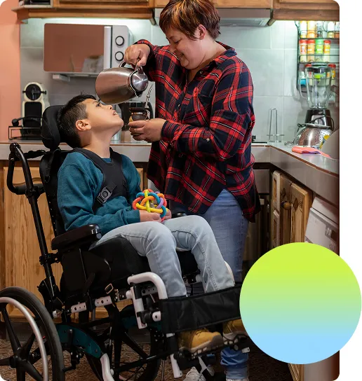 Little kid in an assistive mobility device looking up at his mother in the kitchen