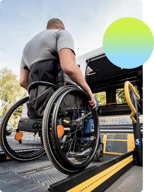 Dramatic shot looking up at a man in a wheelchair using an assistive ramp to get into a vehicle
