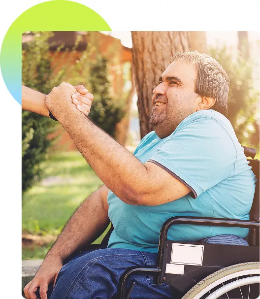 Man in a wheelchair taking a hand and gripping it enthusiastically while looking up