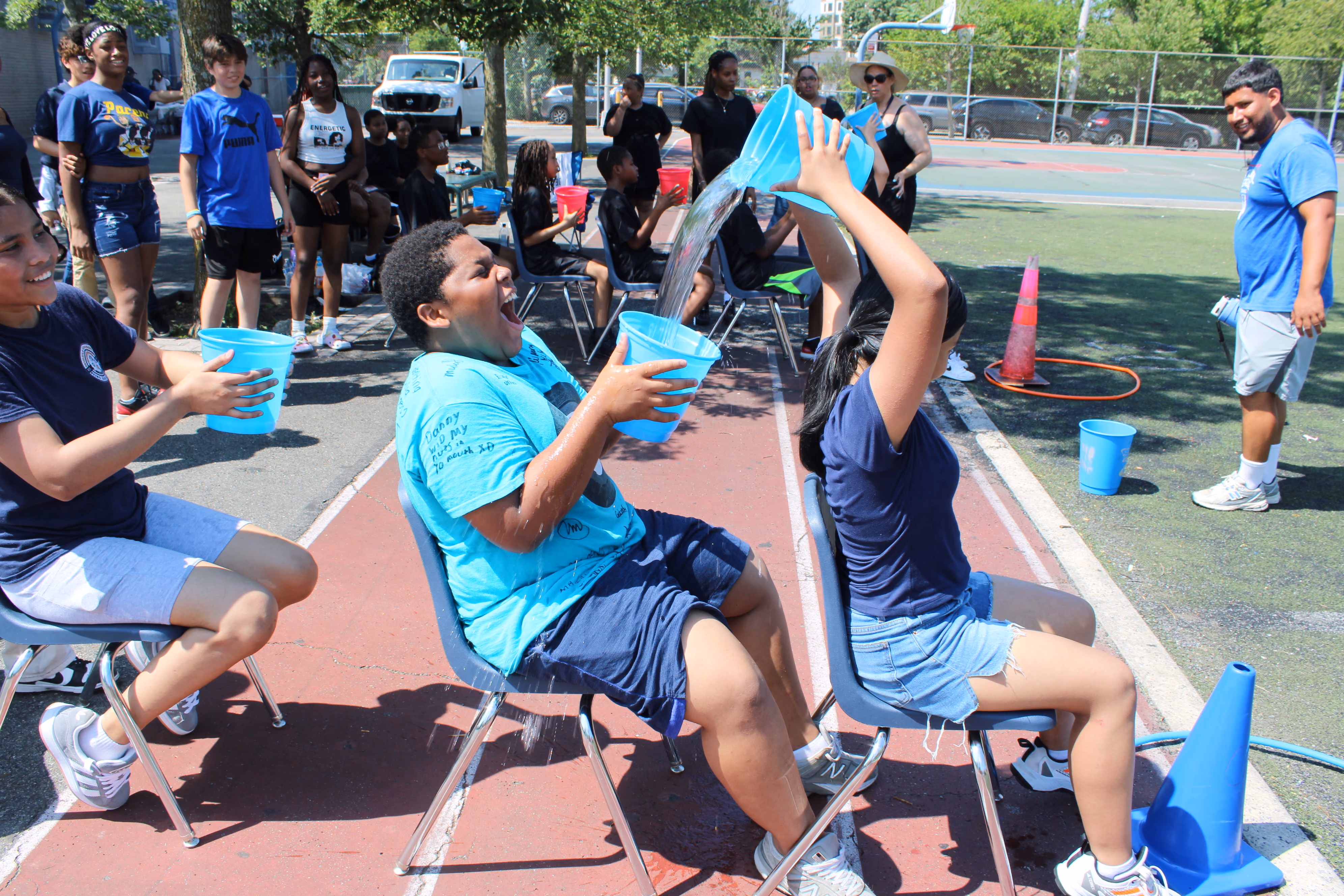Students laugh as water splashes during outdoor field day bucket game
