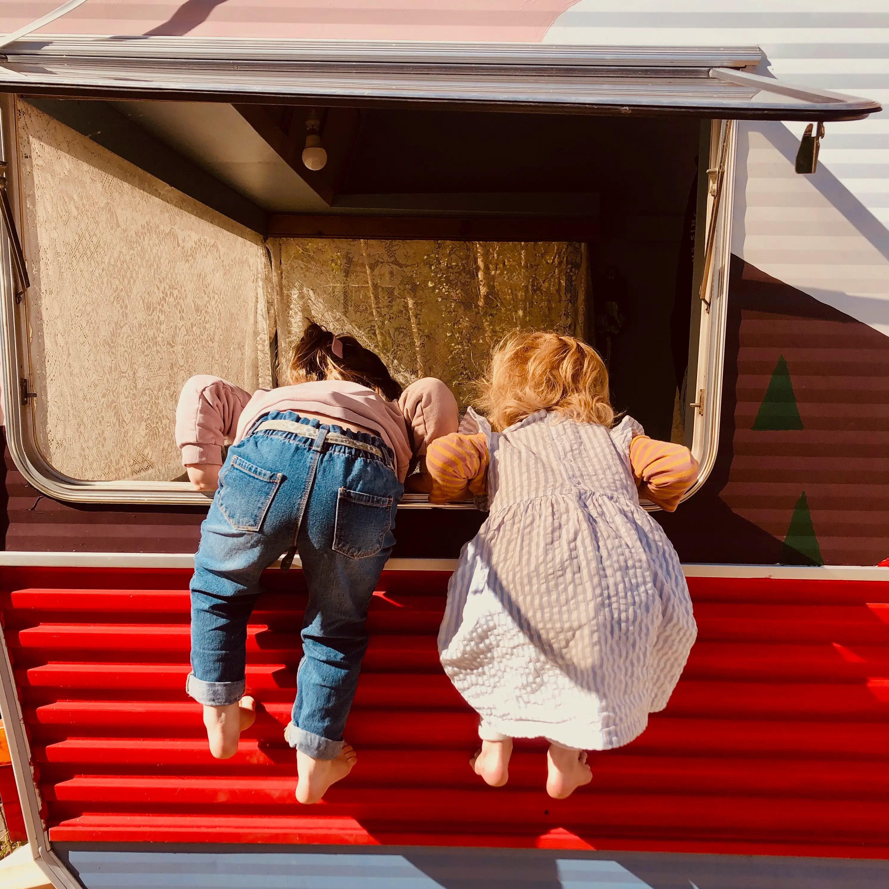 petits enfants grimpent dans l'encadrure d'une fenêtre de caravane