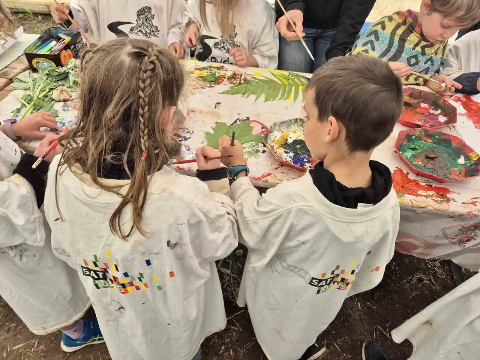 2 enfants dessinant une fresque florale
