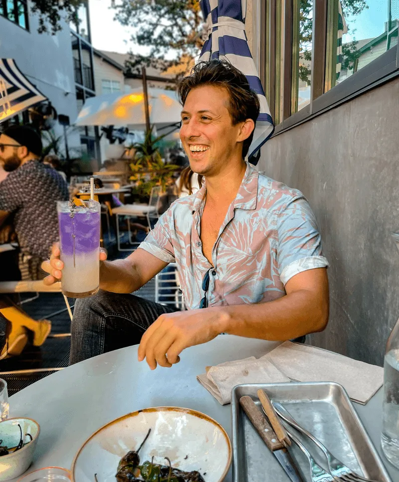 A man sitting at a table with a plate of food and a drink in front of him.