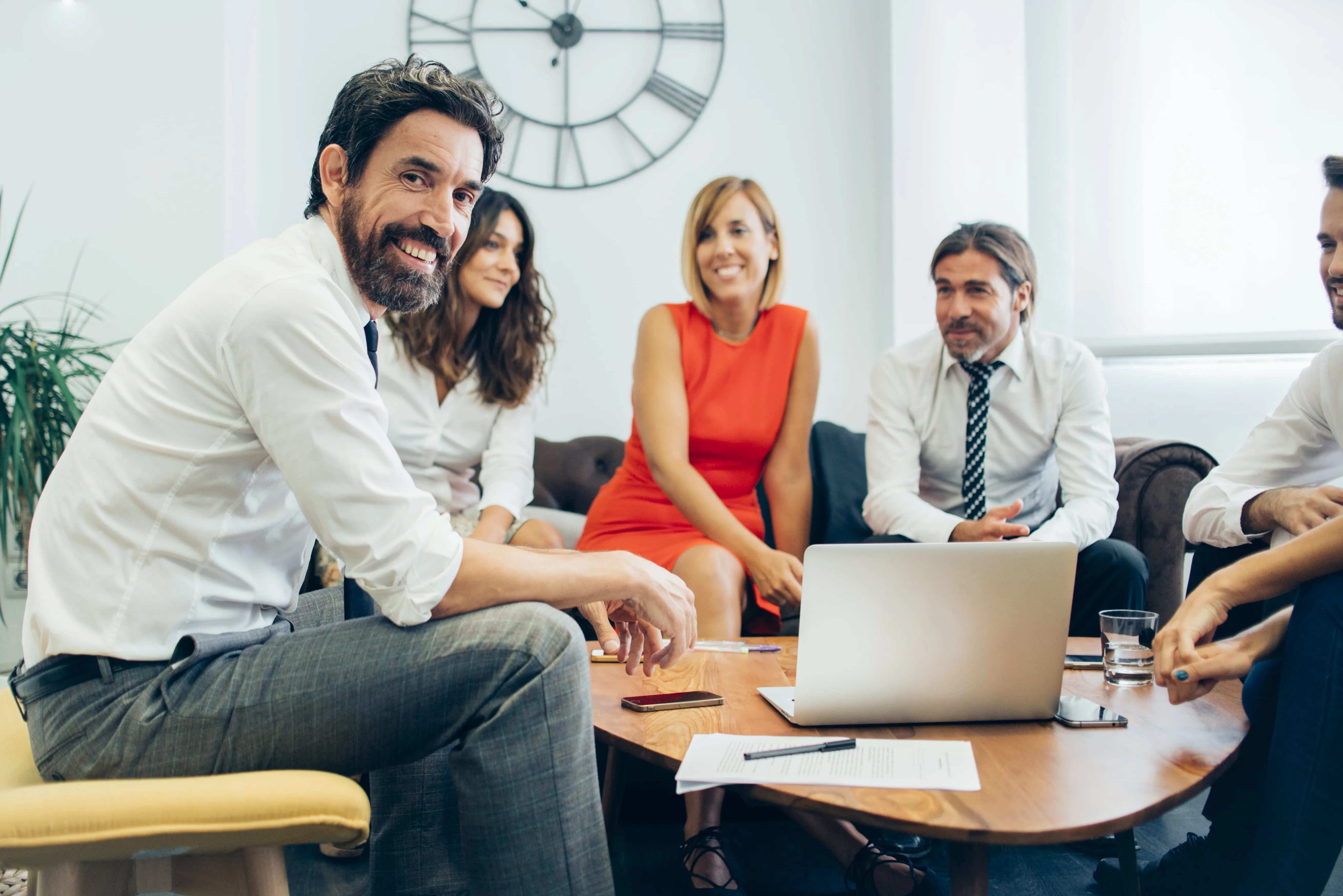 Grupo de cinco profesionales sentados en una sala de reuniones alrededor de una mesa con una computadora portátil abierta.