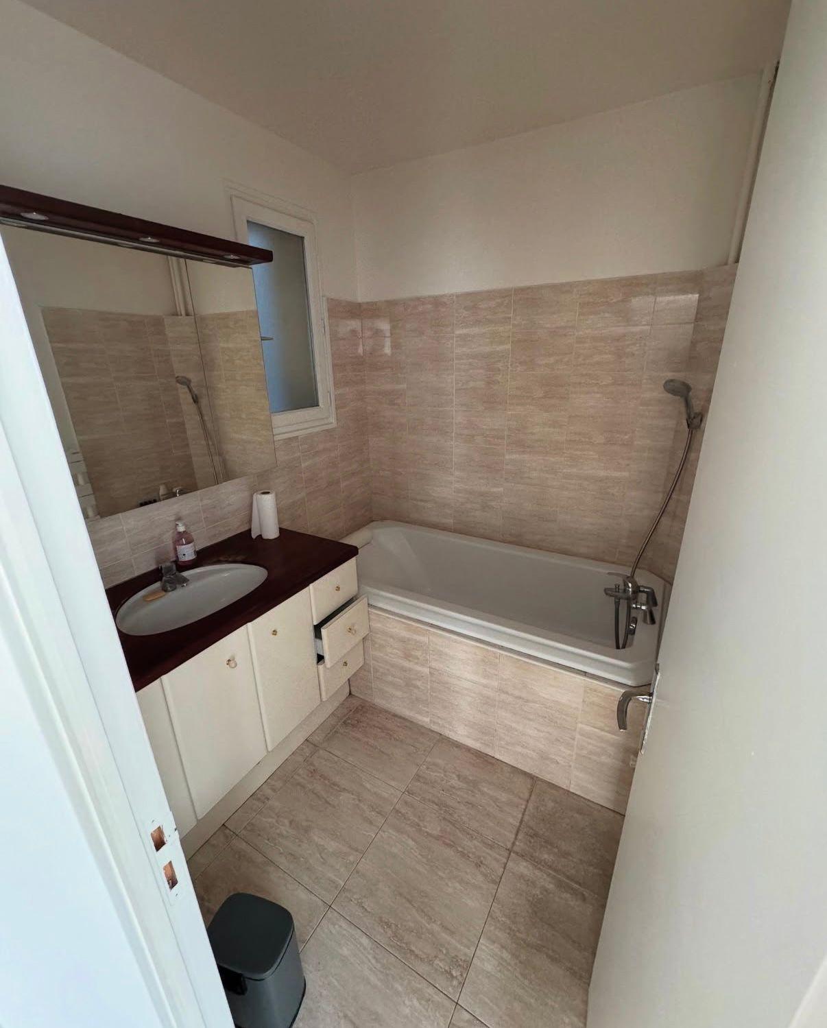 ancienne salle de bain beige avec baignoire et meuble vasque crème, faïence datée.