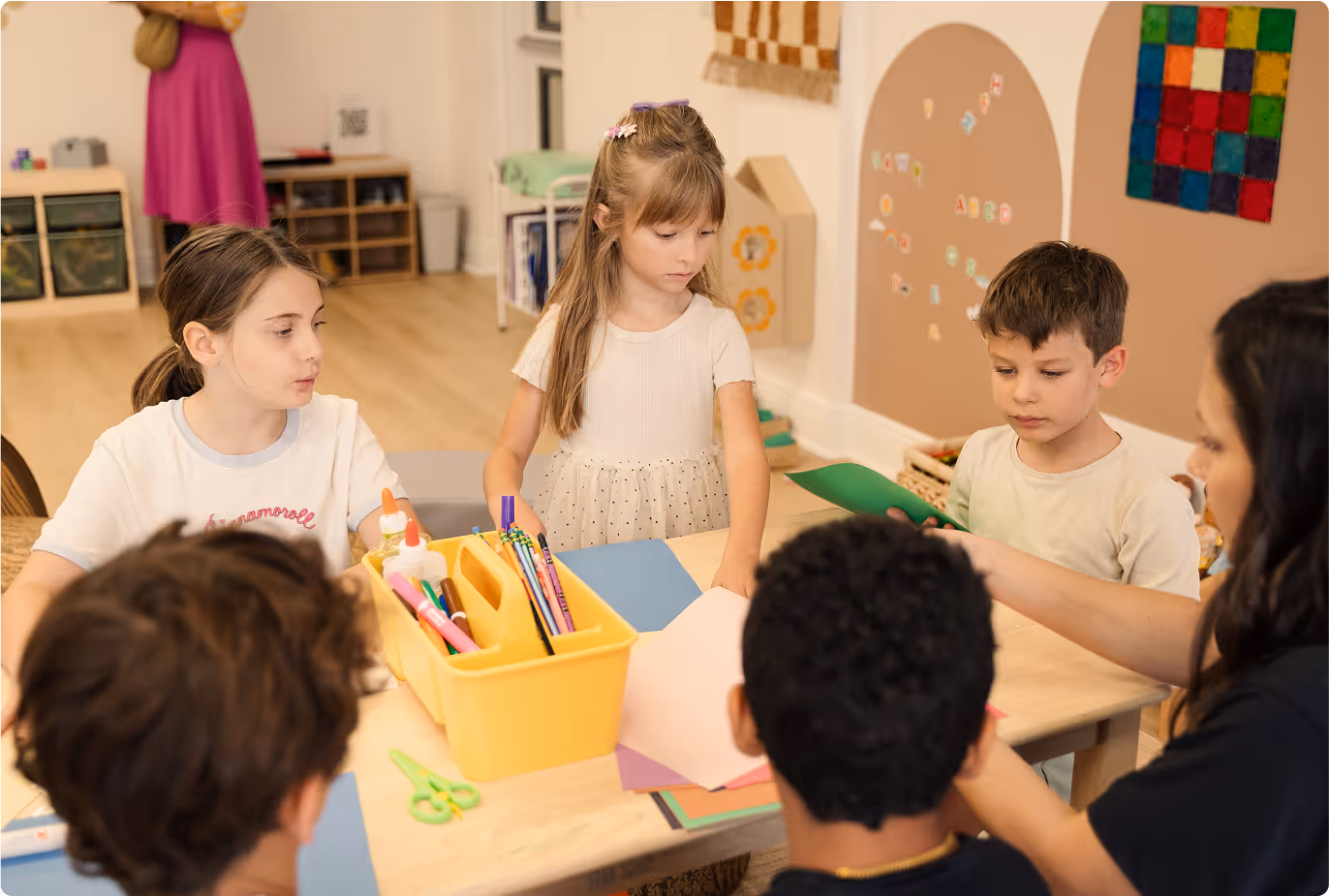Elementary school aged kids working with an adult to make crafts using art supplies