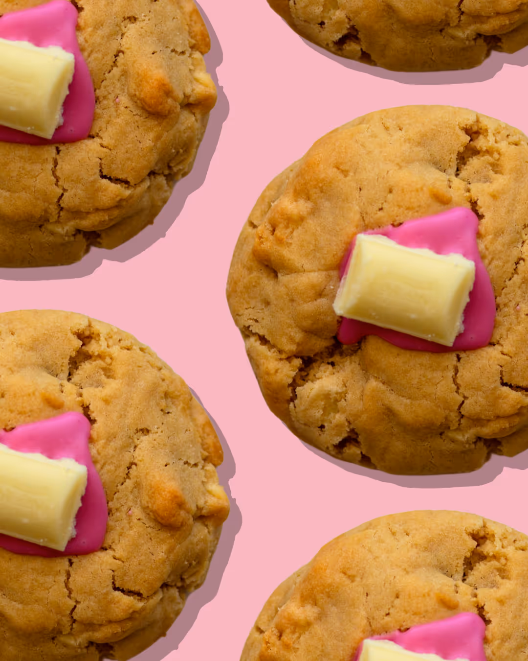 Hands with red nail polish using pink tongs to place a pink frosted cookie with heart sprinkles into a red and white striped 'Sweeet Tooth' bag.