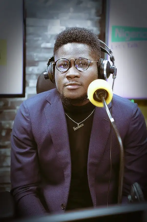 Anthony Devoyce in a studio with mic wearing a suit