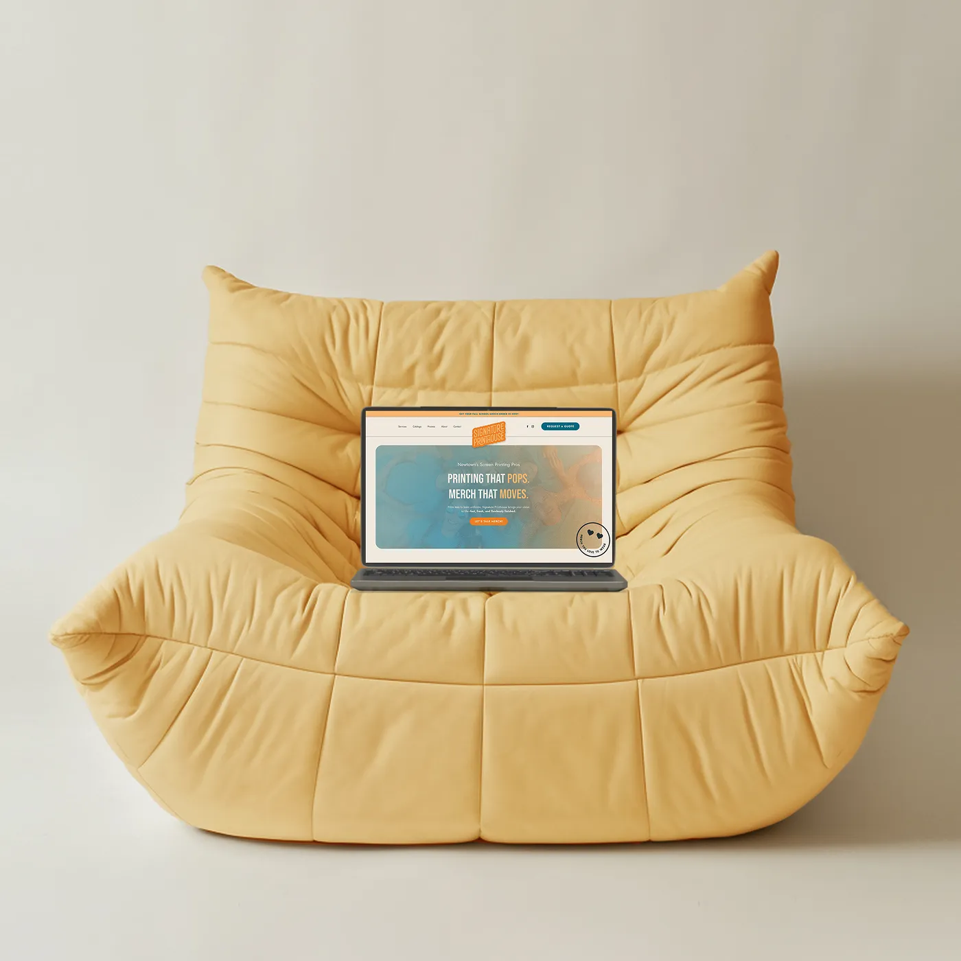 Signature Printhouse website on a laptop on a yellow bean bag chair