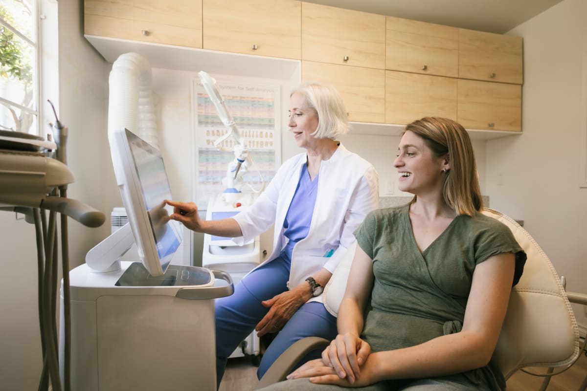 Dentist showing dental implant model to patient in treatment room consultation