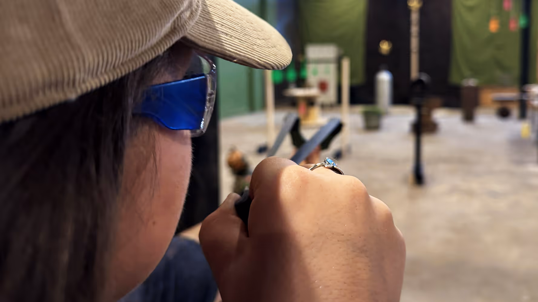 Behind-the-head view of Slingshot Bar guest taking aim at items on the Range with guest in focus.