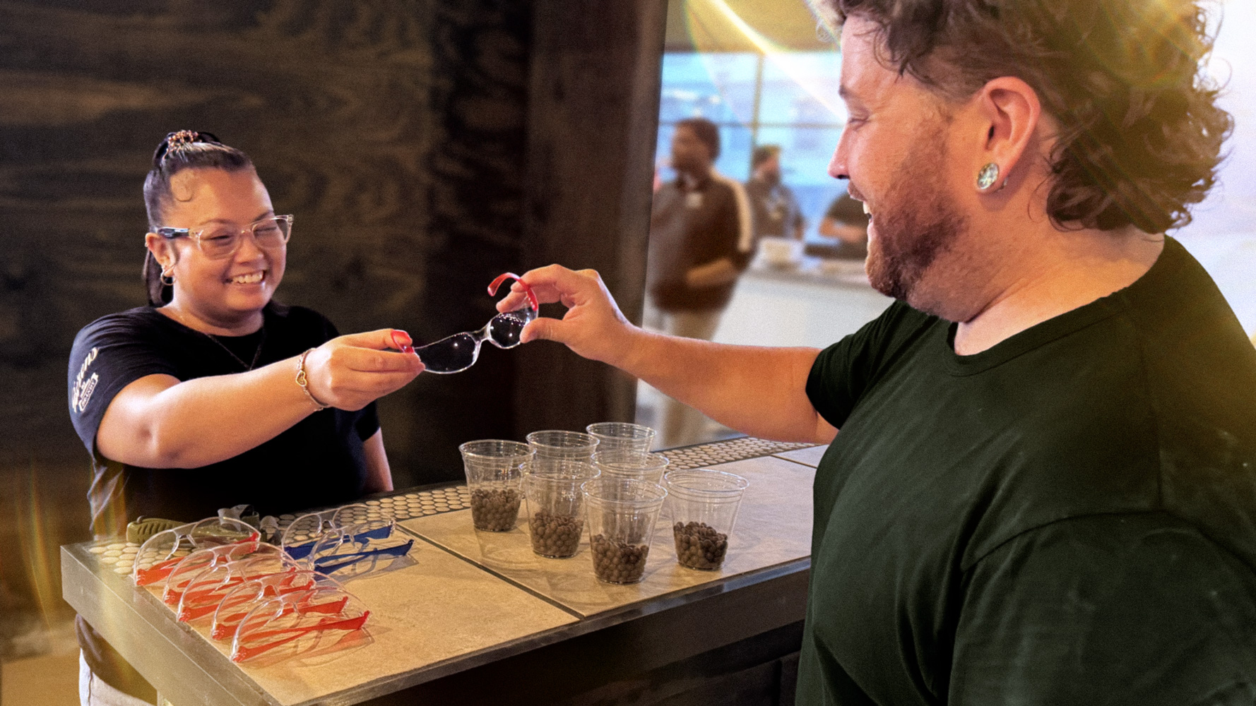 Safety goggles being handed off between smiling employee and guest.