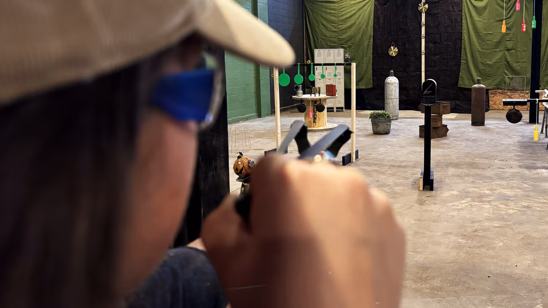 Behind-the-head view of Slingshot Bar guest taking aim at items on the Range with items in focus.