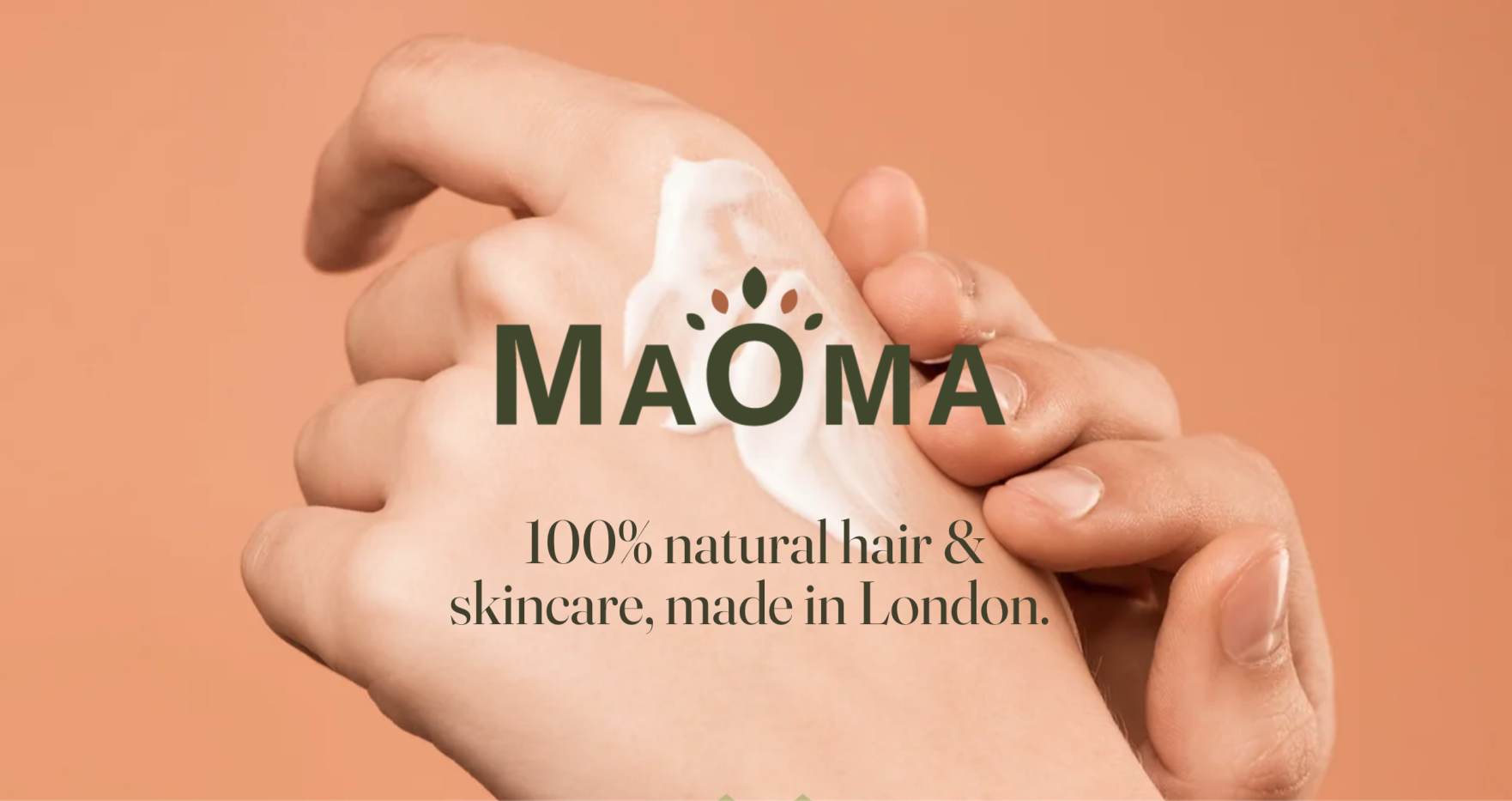 Close-up of a hand applying cream on the back of another hand with Maoma brand text and '100% natural hair & skincare, made in London.'